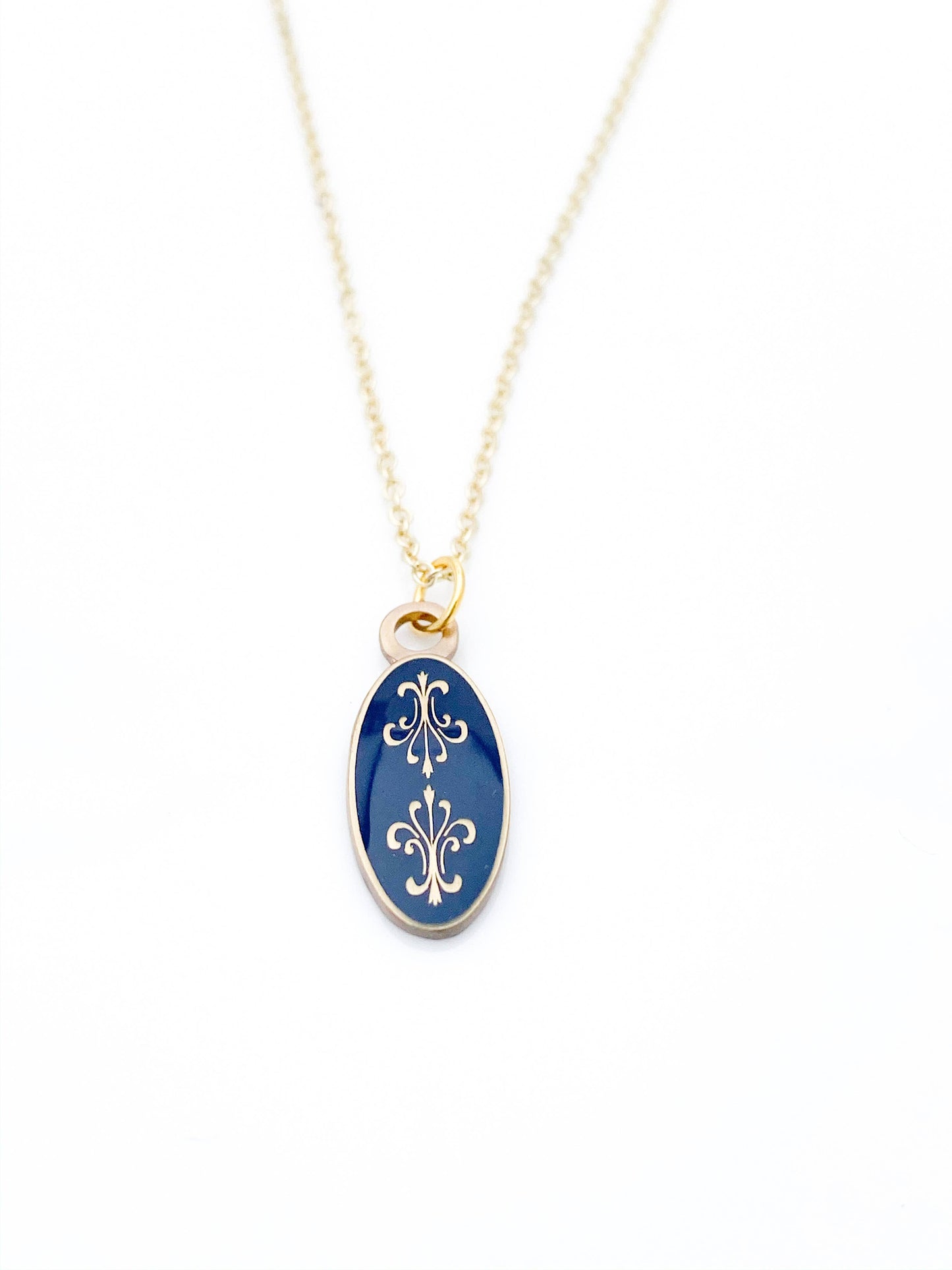 Antiqued gold oval necklace with two fleur de lys back to back on navy blue enamel