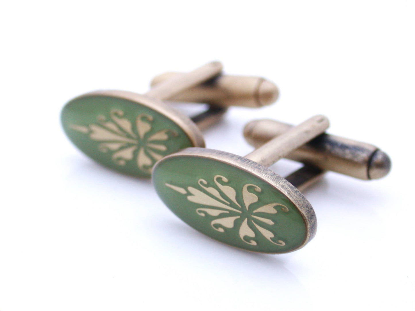 Antiqued gold oval cufflinks with fleur de lys pattern on green enamel