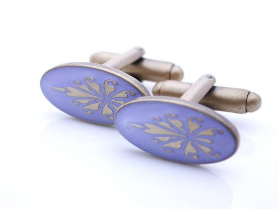 Antiqued gold oval cufflinks with fleur de lys pattern on lilac enamel