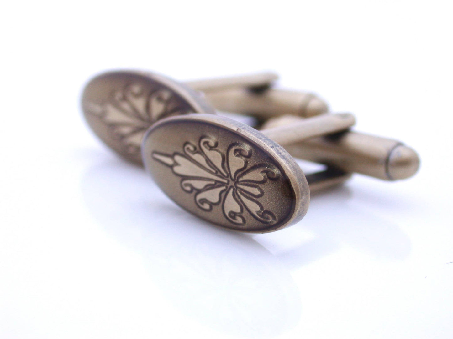 Antiqued gold oval cufflinks with fleur de lys pattern on broze enamel