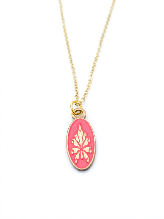 Antiqued gold oval necklace with fleur de lys pattern on coral enamel