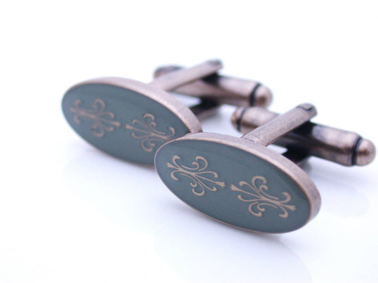 Antiqued gold oval cufflinks with two fleur de lys back to back on gray enamel